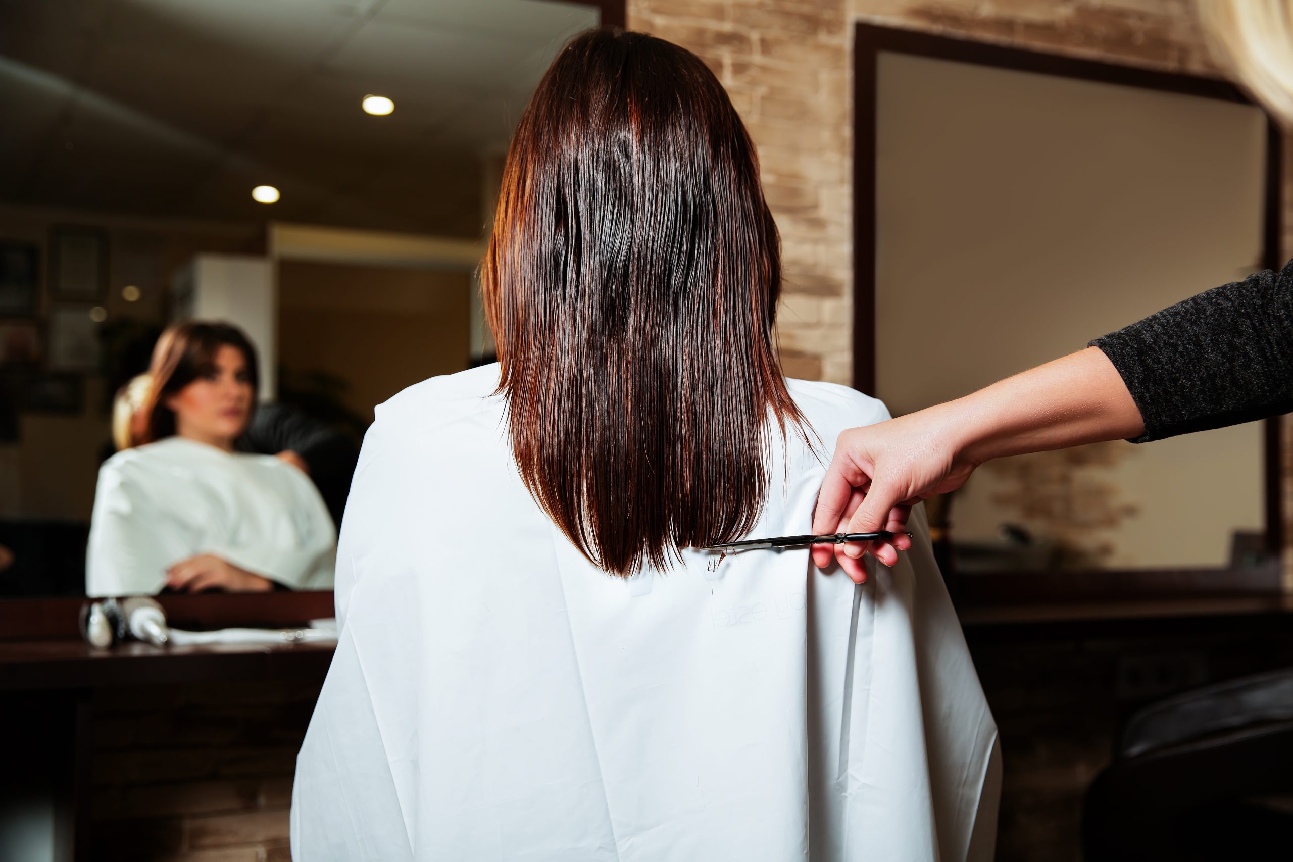 Hairdresser cut long ends to yuong woman